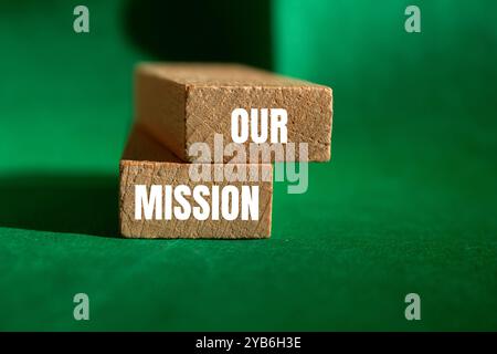 Our mission message written on wooden blocks with green background. Conceptual our mission symbol. Copy space. Stock Photo