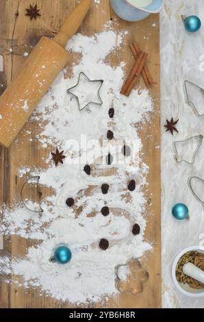 Top view table in kitchen,  preparations for Christmas. Flour, spices, rolling pin, milk, cookie cutters on a table. Stock Photo