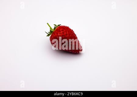 Ripe strawberry casting a shadow on white surface Stock Photo