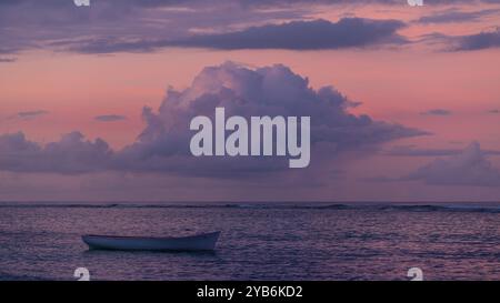 Fishing boat before a pink sunset with big cloud in the sky Stock Photo