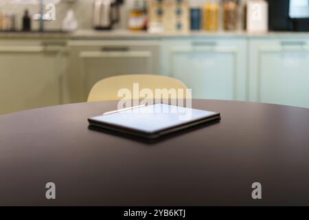 E-reader on kitchen table. Graphic tablet white screen mockup. Home office interior. Stock Photo