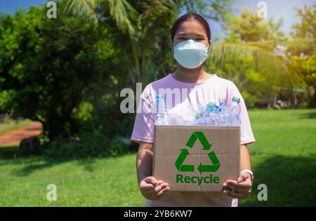 Woman collecting garbage and holding a recycle bin with plastic bottles in the outdoors, Recycle concept, Plastic-free, Junk food plastic packaging, R Stock Photo