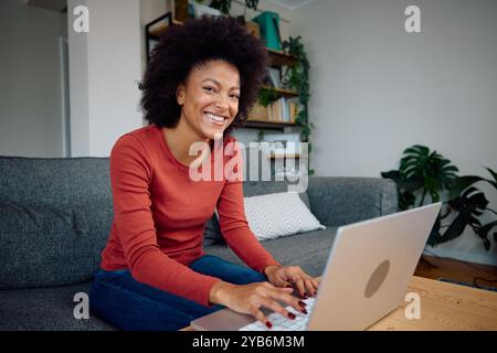 A photo of a mixed race woman using her computer to make notes Stock Photo