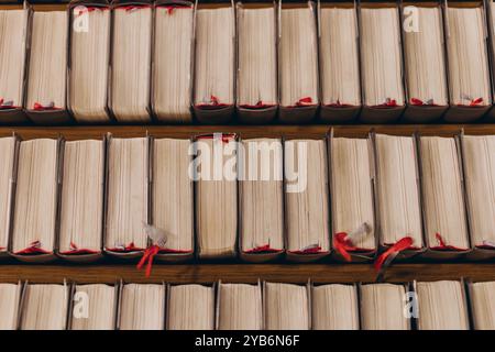 Top-down view of rows of old books with worn pages and red bookmarks,neatly arranged on wooden shelves.High quality photo Stock Photo