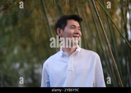side view of smile handsome Asian young man, at bamboo forest Stock Photo