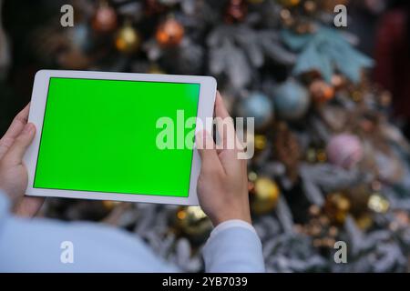 hand holding green screen tablet computer at Christmas. Over the shoulder view Stock Photo