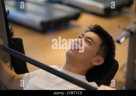 smiling handsome Asian young man workout and exercise in gym Stock Photo