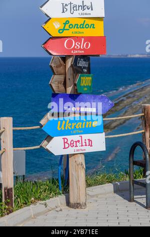 A vibrant collection of directional signs stands proudly along a seaside path, showcasing distances to cities like Istanbul, London, and Oslo, with th Stock Photo