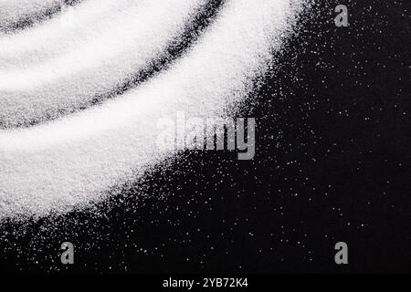 Finely ground stone white rock salt texture on black background, top view Stock Photo