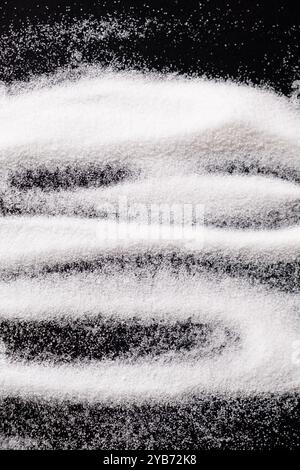 Finely ground stone white rock salt texture on black background, top view Stock Photo