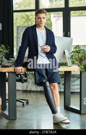 A young businessman with an artificial limb stands confidently in a contemporary office, holding a phone. Stock Photo