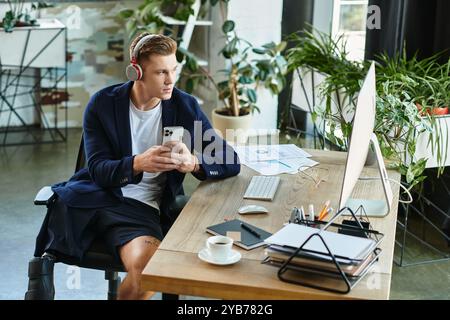 A young businessman with an artificial limb works intently on his smartphone in a bright, modern office. Stock Photo