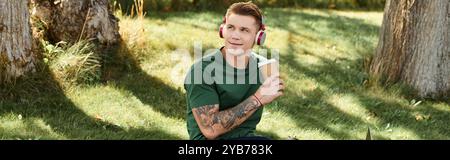 A young man relaxes outdoors, sipping coffee and listening to music with headphones. Stock Photo