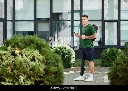 A young man with a prosthetic leg stands confidently outdoors, smiling while holding his phone. Stock Photo