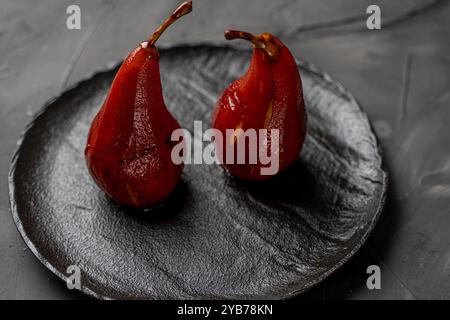 Pears stewed in wine on a black mica plate on a dark background. High quality photo Stock Photo