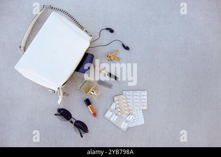 White handbag open with pills and women's accessories. Stock Photo