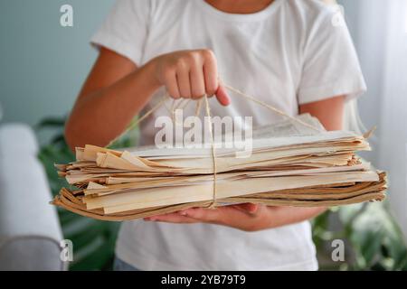 The girl is holding a stack of newspapers in her hands. Ecology. The child hands over paper for waste paper. Stock Photo