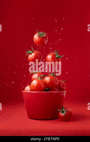 Creative food concept. Tomatoes pattern. Flying red ripe juicy cherry tomatoes with water drops on red background. Healthy fresh vegan organic food, v Stock Photo