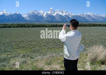 man in mobile photography at Grand Teton, mountain of Teton Range in Grand Teton National Park. Tourist take photo using smartphone Stock Photo