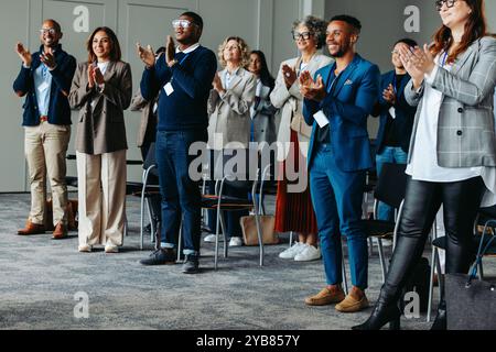 A diverse group of coworkers clapping and applauding during a business conference presentation, showcasing appreciation and support. Stock Photo
