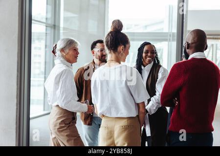 Diverse group of mature business colleagues having a cheerful discussion during a conference in a modern office environment. Stock Photo