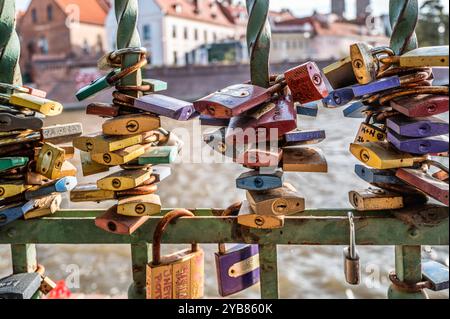 Numerous colorful padlocks symbolize love and commitment as they hang on the railing of a historic bridge, capturing a beautiful urban tradition under Stock Photo