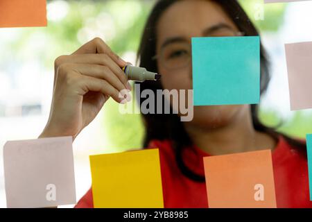A young businesswoman is writing business ideas on a sticky note Stock Photo
