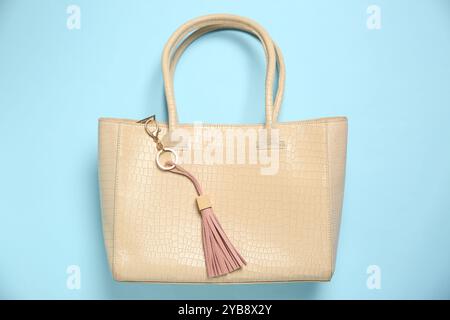 Bag with pink leather keychain on light blue background, top view Stock Photo