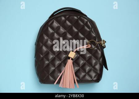 Backpack with pink leather keychain on light blue background, top view Stock Photo