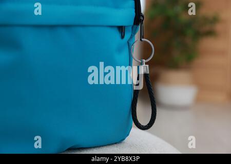 Backpack with black leather keychain on soft surface indoors, closeup. Space for text Stock Photo