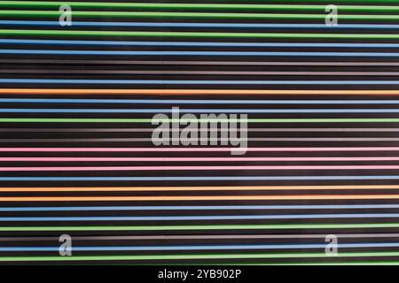Textured wall with horizontal stripes in vibrant colors alternating against dark background. Lines maintain uniform spacing, creating modern, visually Stock Photo