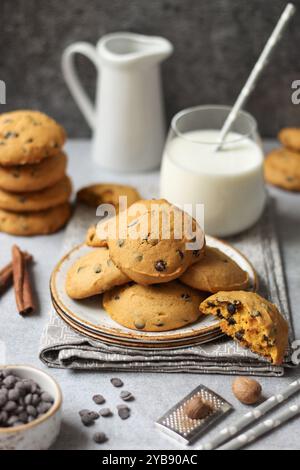 Soft pumpkin chocolate chip cookies with a glass of milk on a grey napkin Stock Photo