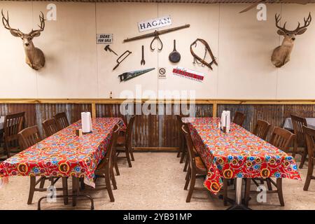 Yoakum, Texas, United States. March 17, 2022. Tables in a small town restaurant, with mounted deer heads and old agricultural equipement as decoration Stock Photo