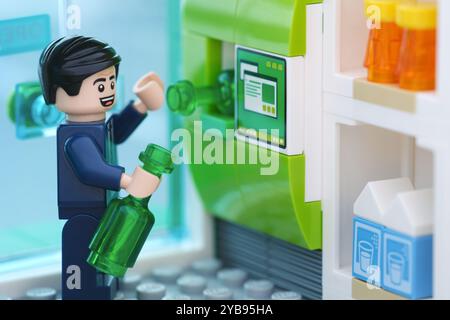 Tambov, Russian Federation - October 15, 2024 A Lego businessman minifigure recycling a used or empty glass bottle at a reverse vending machine in exc Stock Photo