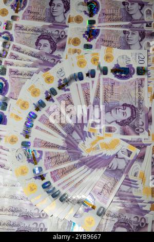 A fan of twenty-pound banknotes arranged on a wooden table. The notes ...