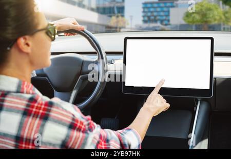 Woman engaging with infotainment system in electric car interior, mockup touchscreen display. Stock Photo