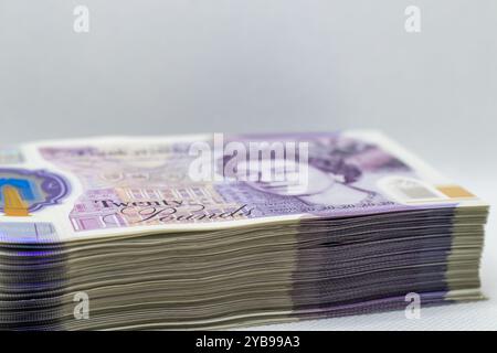 A close-up view of a stack of twenty-pound banknotes, showcasing the intricate details and colors of the currency. The notes are arranged neatly, with Stock Photo