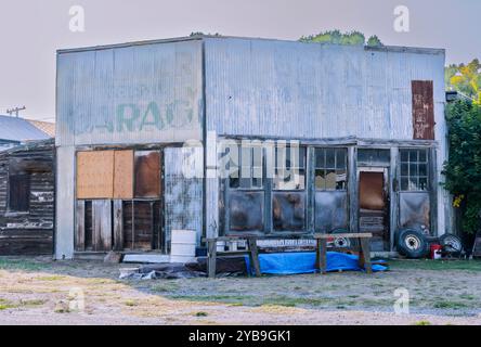 This is an old garage freestanding building made of metal & wood with old broken window panes. You see a corner view, 2 sides are boarded up. Stock Photo