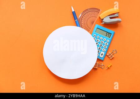 Round blank paper sheet  with calculator and school stationery on orange background Stock Photo