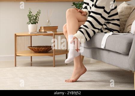 Woman putting white socks on sofa at home Stock Photo