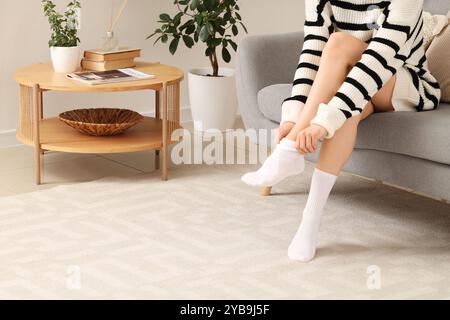 Woman putting white socks on sofa at home Stock Photo