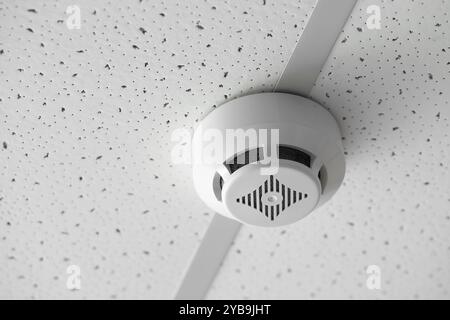 Modern smoke detector on ceiling in room, closeup Stock Photo