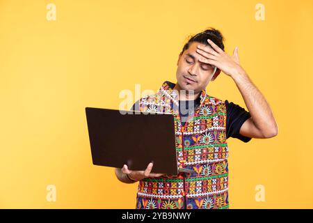 Upset person doing face palm gesturing after seeing error message on laptop screen while doing job tasks, studio background. Overworked employee feeling headache while working Stock Photo