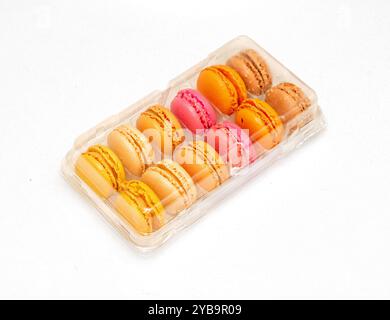 Tasty colorful macarons cakes inside plastic box isolated on white Stock Photo