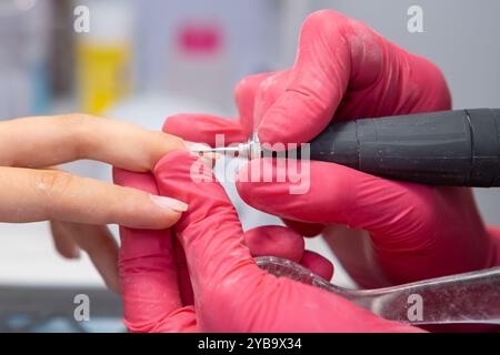 Manicurist uses a nail drill to perfect a woman hardware manicure in a beauty salon Stock Photo