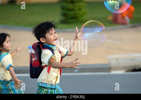 Two children playing bubbles after school in the evening in front of the Royal Palace, Phnom Penh, Cambodia. Stock Photo