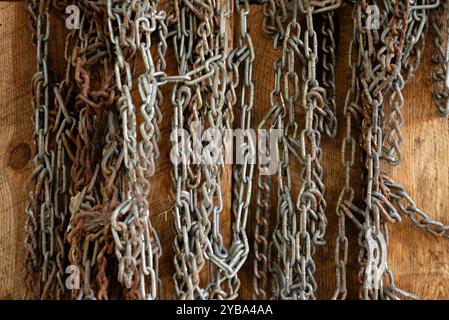Metal work chains hang on the wall of a shed, USA. Stock Photo