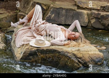 Blonde beauty shines in stunning fall attire near park waterfall, a picturesque autumn scene Stock Photo