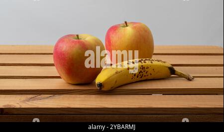 Two ripe, crisp apples and a ripe banana with some black spots Stock Photo