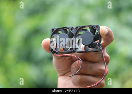 Cooling fan that is used in computer and other electronics to cool the processors by providing air supply held in the hand on natural background Stock Photo